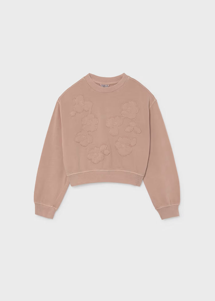 A dusty rose crewneck sweatshirt with tonal floral applique detailing on the front, displayed flat against a light gray background.