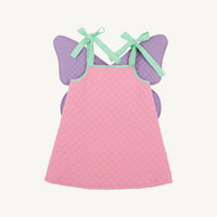 A pink quilted baby dress with purple fairy wings and mint green ribbon shoulder straps, shown flat on a light cream background.
