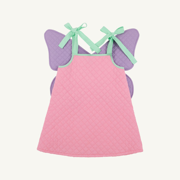 A pink quilted baby dress with purple fairy wings and mint green ribbon shoulder straps, shown flat on a light cream background.
