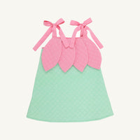 A quilted baby dress with a mint green body and a pink leaf-shaped bodice with tie straps, shown on a light cream background.