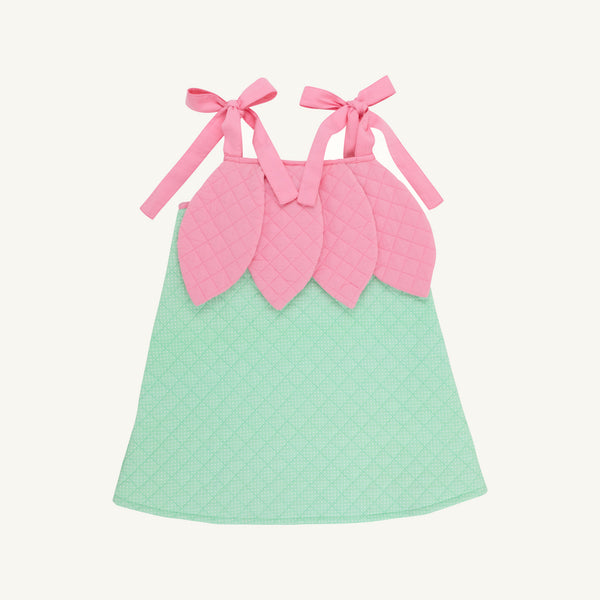 A quilted baby dress with a mint green body and a pink leaf-shaped bodice with tie straps, shown on a light cream background.