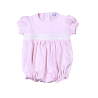 Pink baby romper with lace detail on a white background