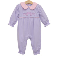 A baby girl's long-sleeve footless romper with lavender and white stripes, a pink Peter Pan collar, and pink bow embroidery on the chest, hanging on a wooden hanger against a white background.