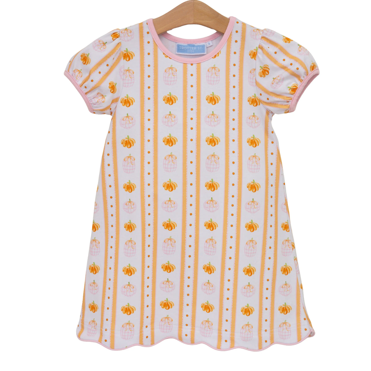 A short-sleeve baby dress with puff sleeves, featuring vertical stripes of orange pumpkins, pink crowns, and gold dots on a white background, hanging on a wooden hanger against a white background.