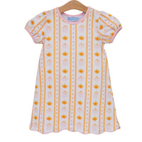 A short-sleeve baby dress with puff sleeves, featuring vertical stripes of orange pumpkins, pink crowns, and gold dots on a white background, hanging on a wooden hanger against a white background.