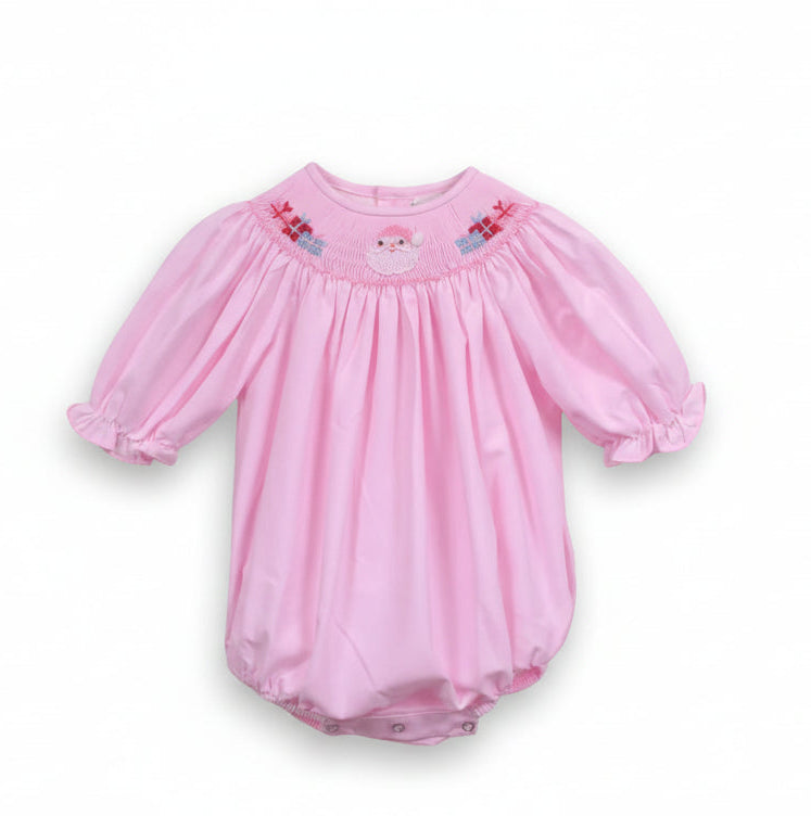 A baby girl's pink long-sleeve romper with puff sleeves, featuring a smocked yoke with a small embroidered Santa face and gift details, hanging on a white hanger against a white background.